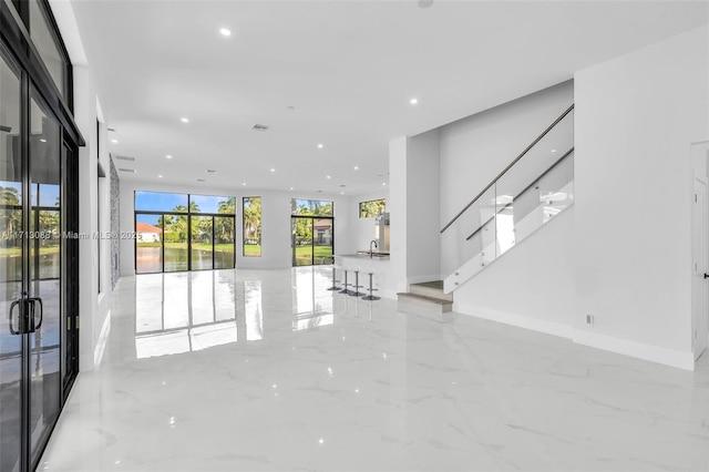 unfurnished living room featuring stairway, recessed lighting, baseboards, floor to ceiling windows, and marble finish floor
