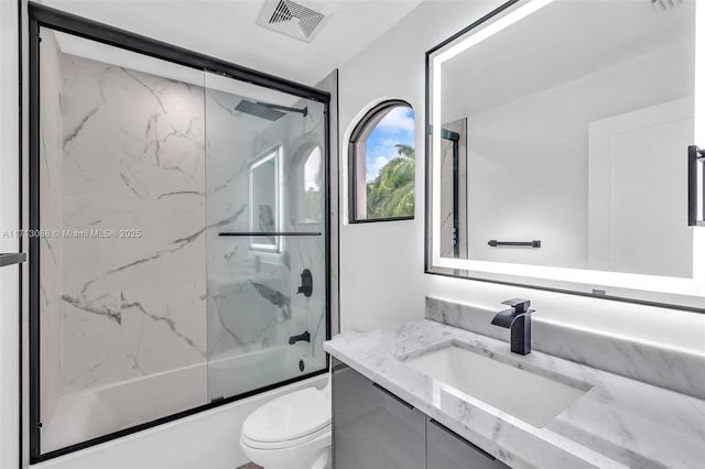 bathroom with visible vents, toilet, vanity, and enclosed tub / shower combo