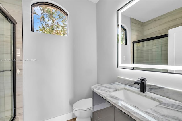 bathroom featuring toilet, vanity, tile patterned floors, and an enclosed shower