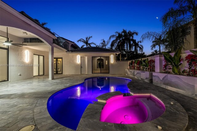 pool at dusk with an in ground hot tub and a patio area