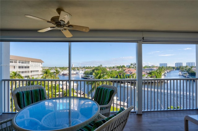 sunroom / solarium with a water view and ceiling fan