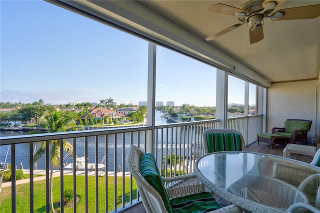 sunroom / solarium with ceiling fan and a water view
