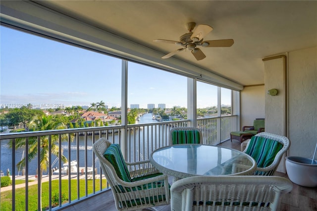 sunroom / solarium with ceiling fan and a water view