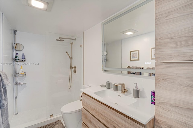 bathroom with vanity, toilet, and tiled shower