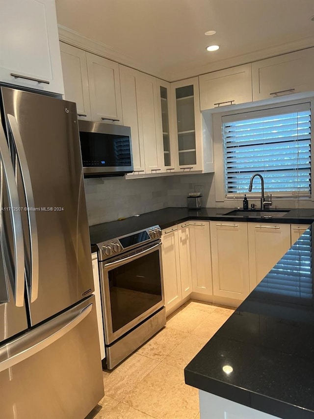 kitchen featuring white cabinetry, sink, tasteful backsplash, light tile patterned floors, and appliances with stainless steel finishes