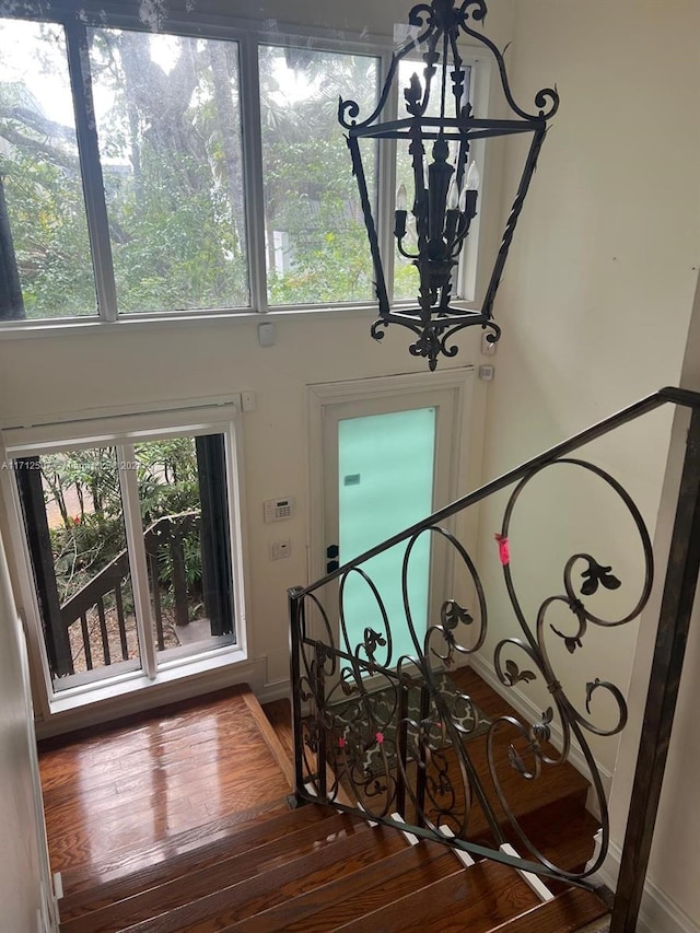 stairs with wood-type flooring and an inviting chandelier