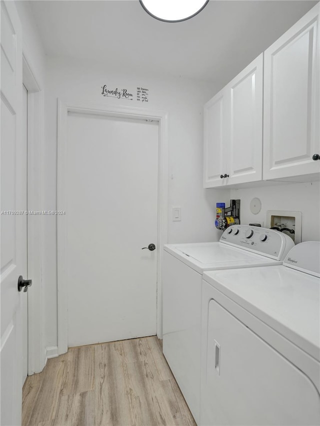 clothes washing area featuring washer and dryer, cabinets, and light hardwood / wood-style flooring