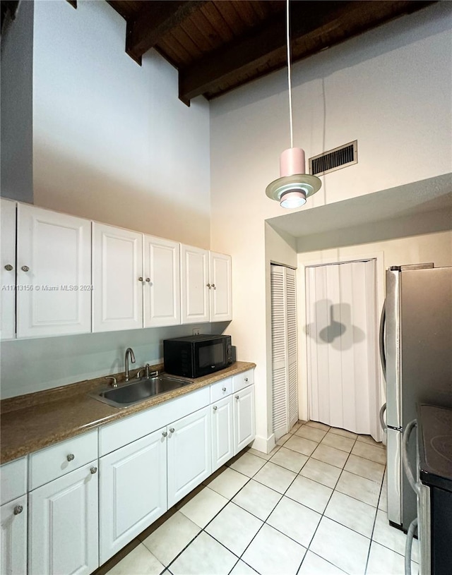 kitchen featuring a high ceiling, sink, light tile patterned floors, beamed ceiling, and white cabinetry