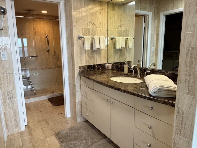 bathroom featuring vanity, an enclosed shower, and tile walls