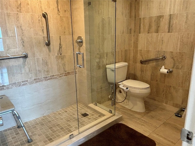 bathroom featuring tile patterned floors, toilet, walk in shower, and tile walls