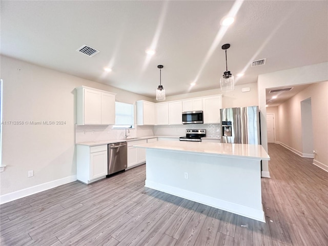 kitchen featuring decorative light fixtures, white cabinetry, and appliances with stainless steel finishes