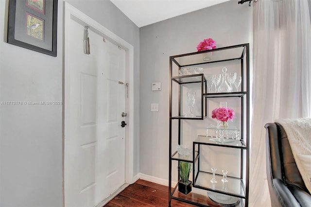 foyer entrance with dark wood finished floors and baseboards