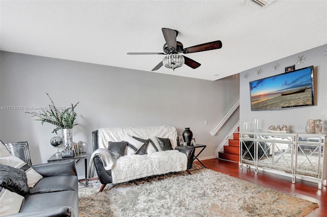 living room featuring baseboards, ceiling fan, stairway, wood finished floors, and a textured ceiling