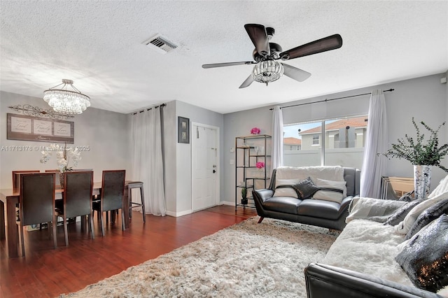 living room featuring visible vents, ceiling fan with notable chandelier, a textured ceiling, wood finished floors, and baseboards