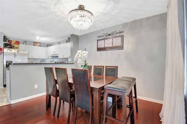 dining room featuring an inviting chandelier, wood finished floors, and baseboards