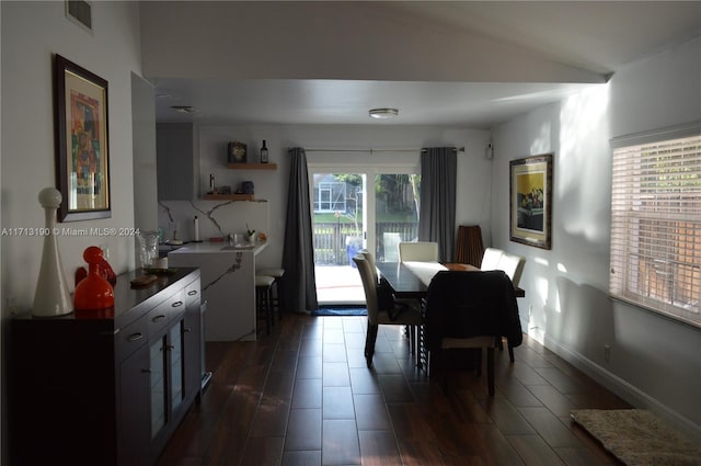 dining area with vaulted ceiling and dark wood-type flooring