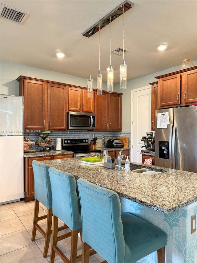 kitchen with backsplash, sink, decorative light fixtures, and appliances with stainless steel finishes