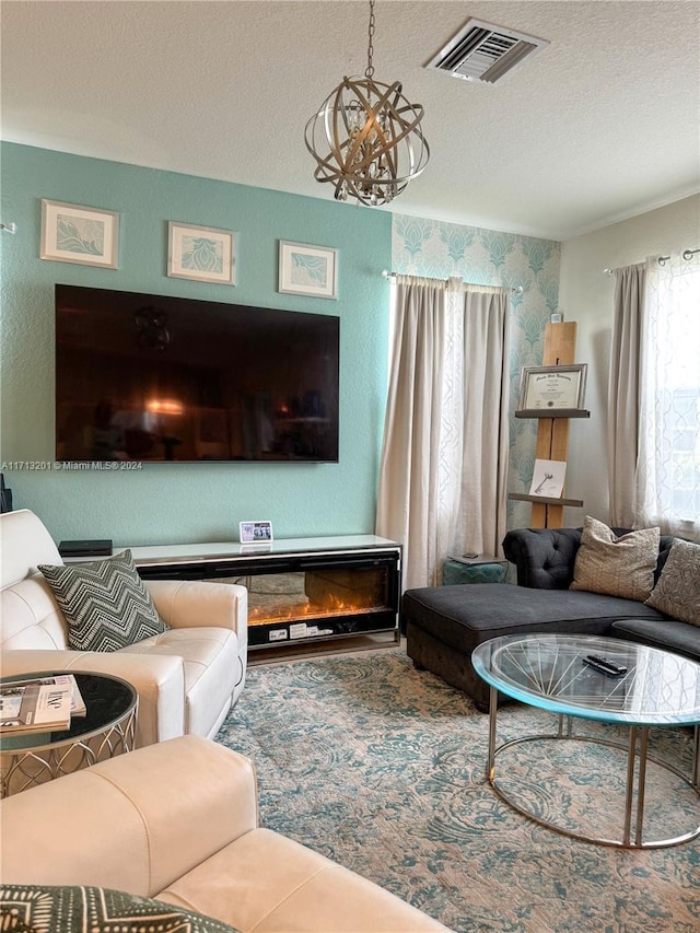 living room with a fireplace, a textured ceiling, and an inviting chandelier