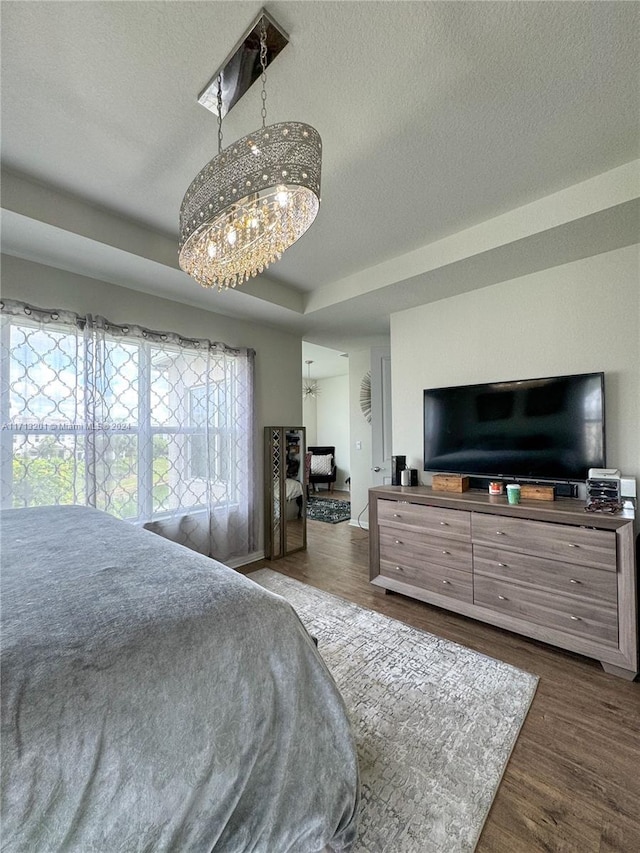 bedroom with a textured ceiling, multiple windows, a chandelier, and dark hardwood / wood-style floors