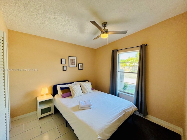 tiled bedroom with ceiling fan, a textured ceiling, and vaulted ceiling