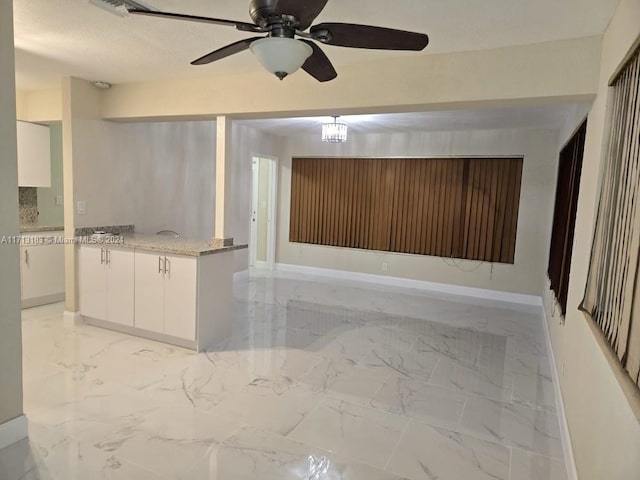 interior space featuring ceiling fan, light stone countertops, white cabinetry, and a textured ceiling