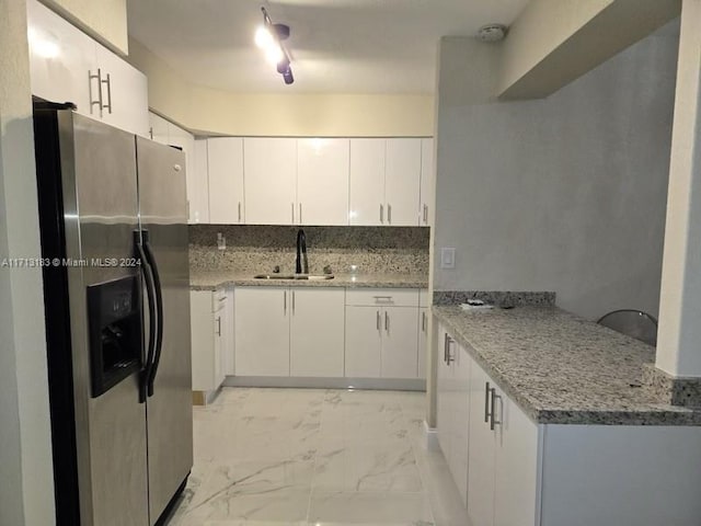 kitchen featuring white cabinets, stainless steel fridge with ice dispenser, light stone countertops, and sink