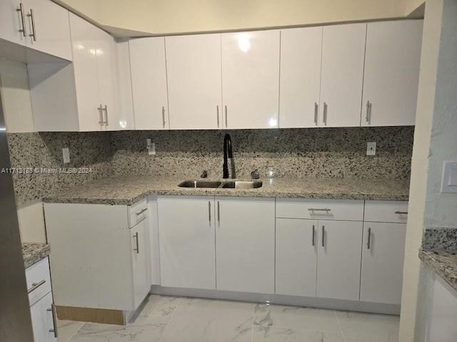 kitchen with backsplash, white cabinetry, and sink