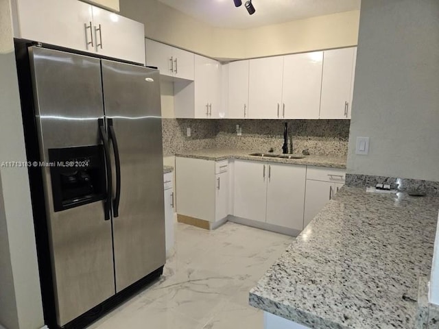 kitchen featuring white cabinets, stainless steel refrigerator with ice dispenser, decorative backsplash, and sink