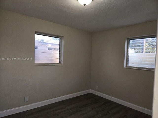 spare room with dark hardwood / wood-style floors, a healthy amount of sunlight, and a textured ceiling