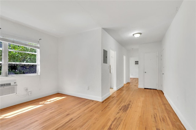 empty room featuring light hardwood / wood-style floors, electric panel, and a wall mounted AC