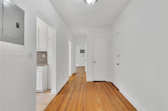 hallway featuring electric panel and light hardwood / wood-style flooring