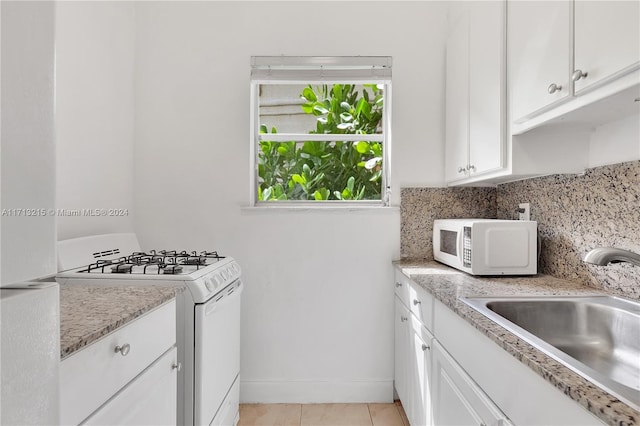 kitchen featuring white appliances, white cabinets, sink, light tile patterned floors, and tasteful backsplash