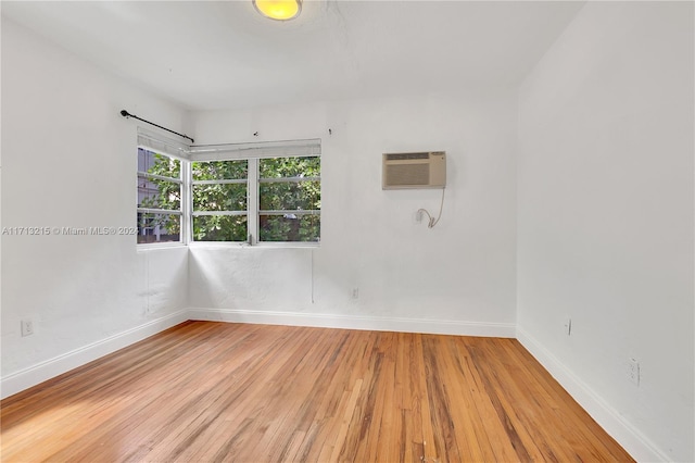 unfurnished room with a wall mounted air conditioner and wood-type flooring