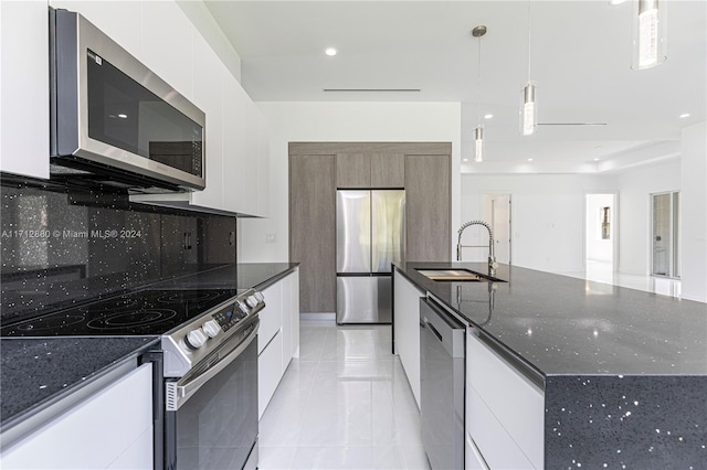 kitchen with appliances with stainless steel finishes, pendant lighting, tasteful backsplash, white cabinetry, and sink