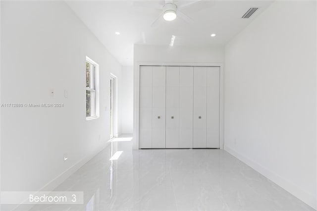 unfurnished bedroom with ceiling fan and a closet