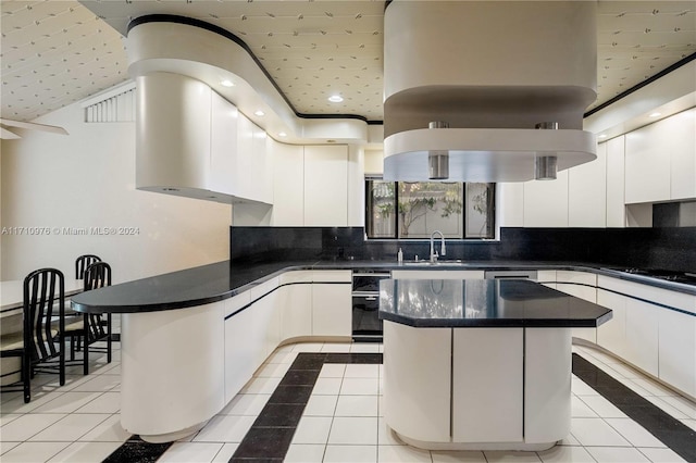 kitchen featuring a center island, sink, gas stovetop, light tile patterned flooring, and white cabinetry