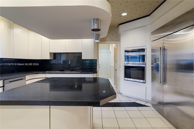 kitchen with a center island, light tile patterned floors, tasteful backsplash, white cabinetry, and stainless steel appliances