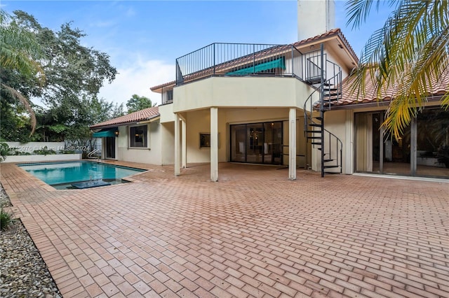 back of property featuring a fenced in pool, a patio area, and a balcony