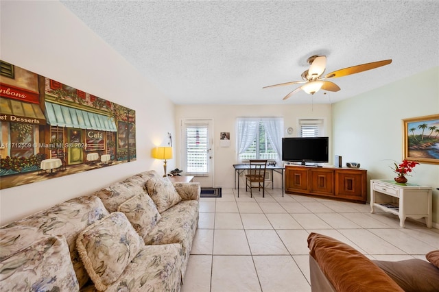 living room featuring ceiling fan, light tile patterned floors, and a textured ceiling