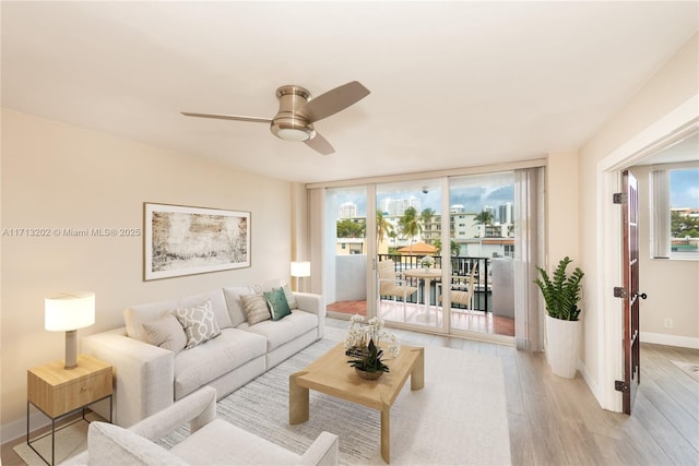 living room with floor to ceiling windows, ceiling fan, plenty of natural light, and light hardwood / wood-style floors