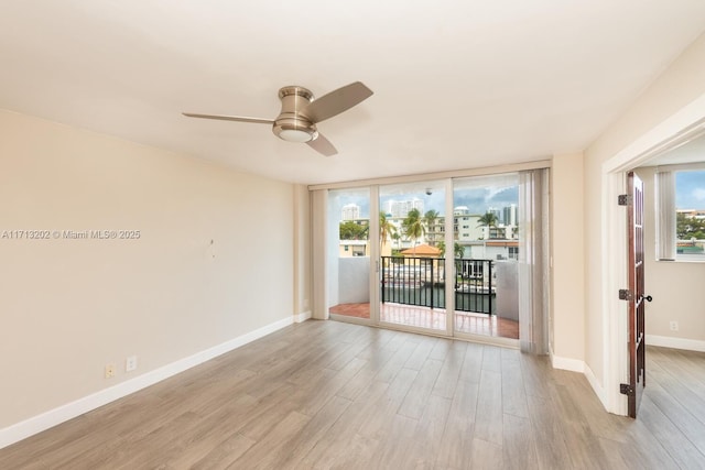 unfurnished room with ceiling fan, a wall of windows, and light wood-type flooring