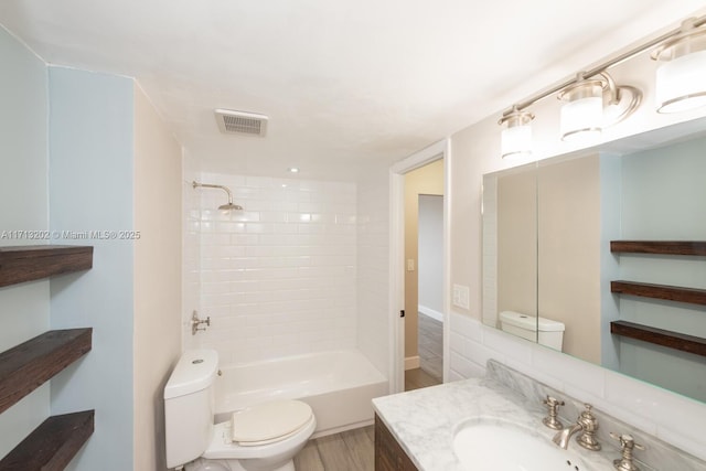 full bathroom featuring backsplash, vanity, hardwood / wood-style floors, toilet, and tiled shower / bath