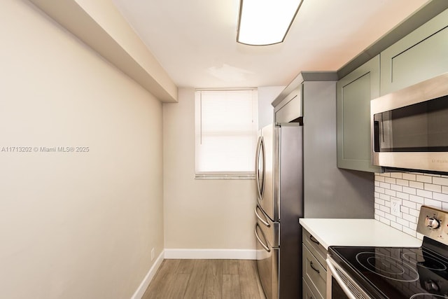 kitchen with light wood-type flooring, backsplash, stainless steel appliances, and green cabinets