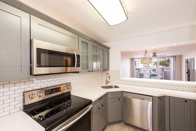 kitchen with decorative backsplash, stainless steel appliances, hanging light fixtures, and sink