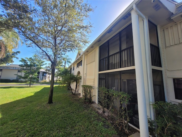 view of side of property featuring a lawn and a sunroom