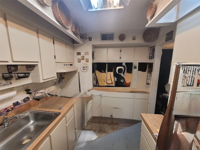 kitchen featuring white cabinets, wooden counters, and sink