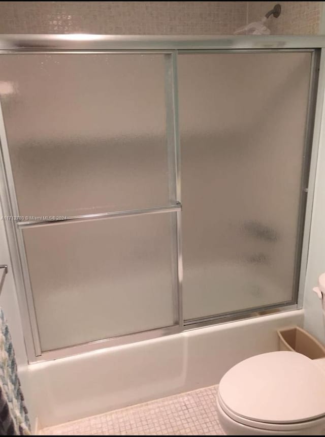 bathroom with shower / bath combination with glass door, tile patterned floors, and toilet