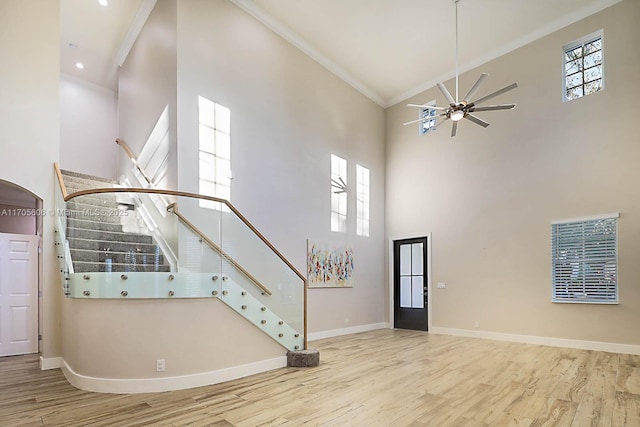 foyer entrance with a high ceiling, light hardwood / wood-style floors, ceiling fan, and crown molding