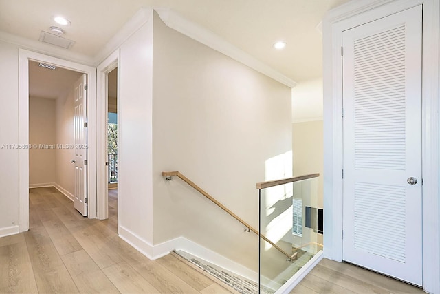 hall with light wood-type flooring and ornamental molding