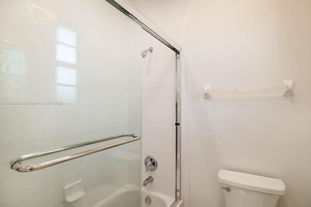 bathroom with combined bath / shower with glass door and toilet